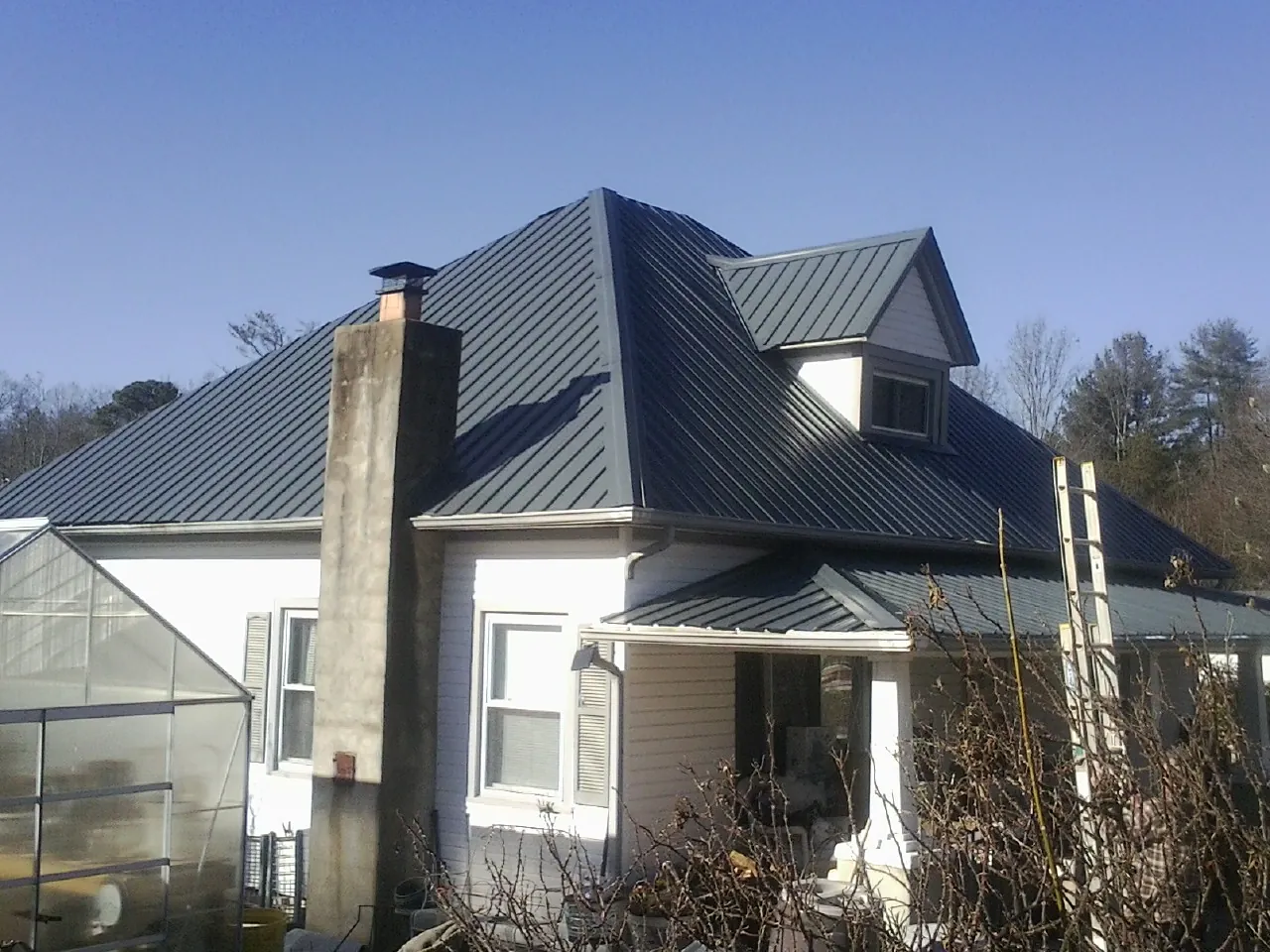 Dark blue standing seam metal roof on a white farmhouse with dormer — Slate & Tile Roof Repair by Roofing Brothers in Gratz