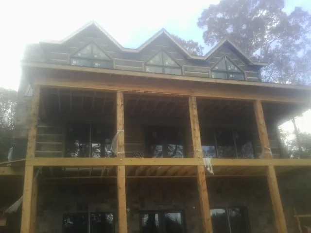 Dormers and porch framing on a large log home under construction — Roof Coating work by our crew in Gratz
