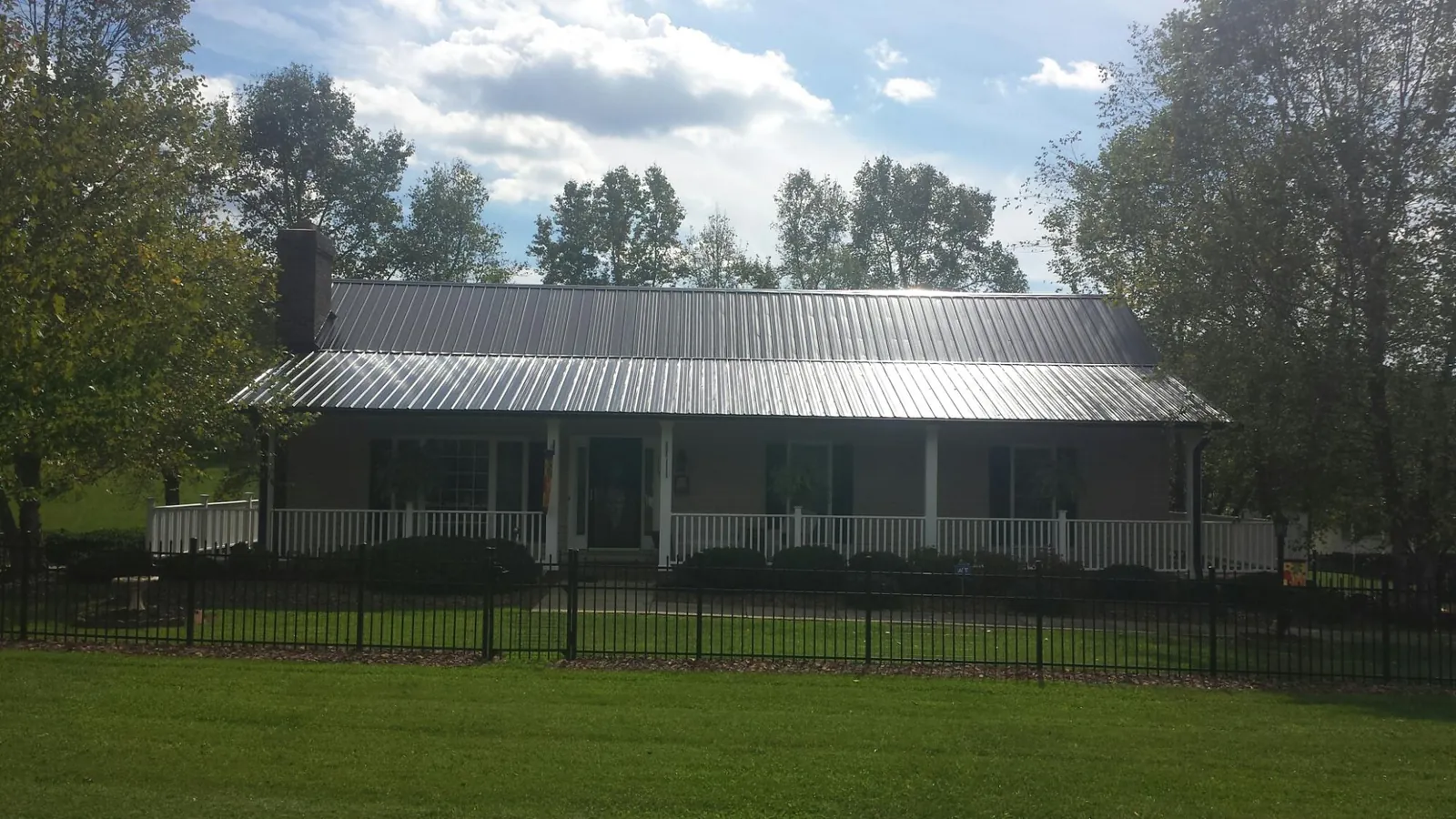 Gray metal roof on a brick ranch with a full width front porch — Gutter Guard Installation work by our crew in Gratz