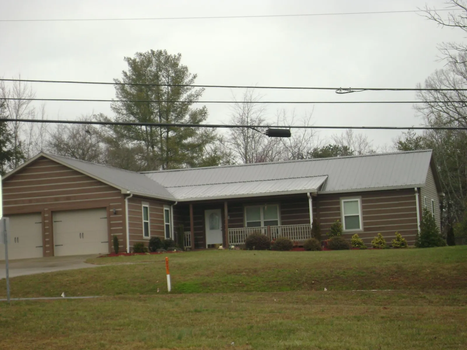 Gray metal roof on a log sided ranch home with a front porch in Gratz