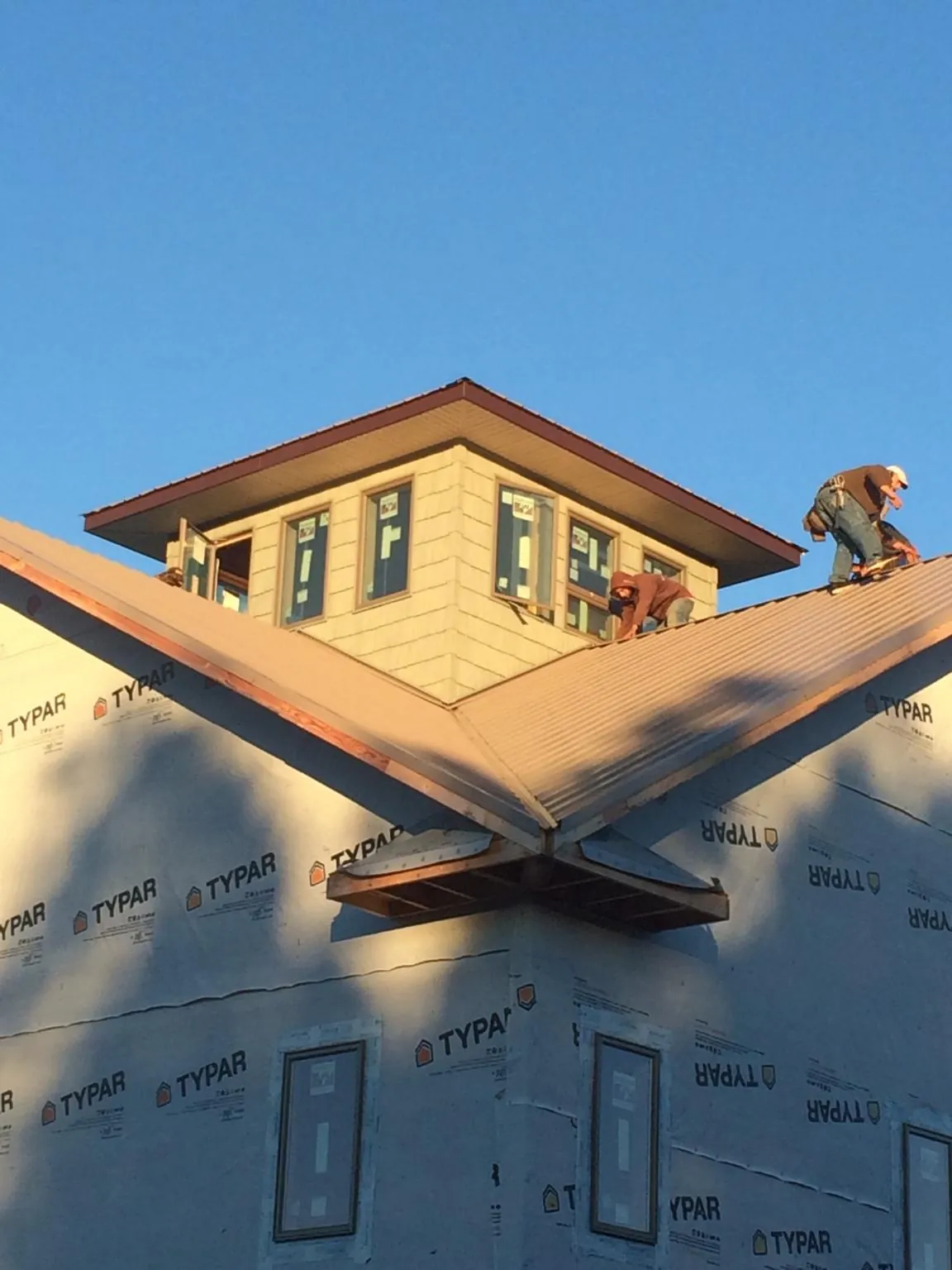 Roofers working around a rooftop cupola on a new metal roof at sunset — Roof Waterproofing in Gratz by Roofing Brothers